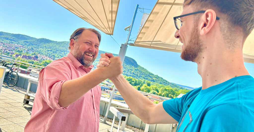 Two colleagues celebrating a successful collaboration with a handshake, symbolising partnership and teamwork in market entry strategies.