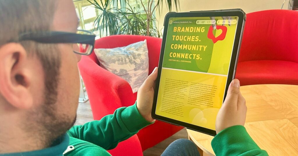 Person holding a tablet in a relaxed office environment, reading the Handelskraft Trend Book on the future of digital business.