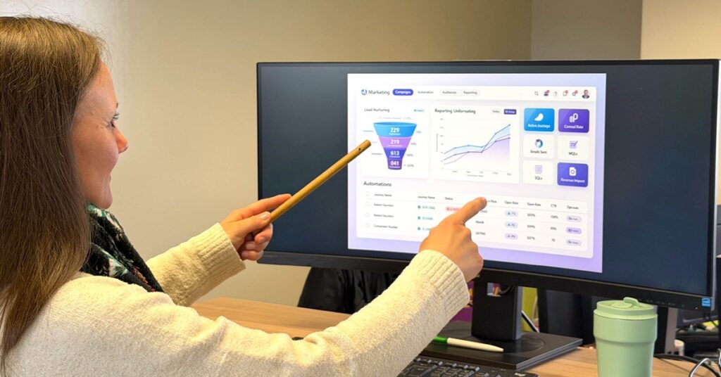 Person pointing at a marketing automation dashboard displaying lead tracking and campaign performance metrics.