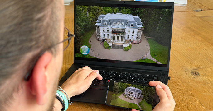Person watching the same video of a villa on laptop and smartphone, demonstrating hyper-personalized cross‑device experiences.