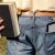 Man with book and e-reader in jeans pocket in grass field